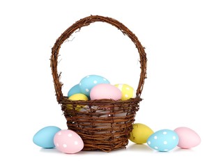 Easter basket filled with colorful hand painted blue, pink and yellow Easter Eggs over a white background