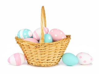 Easter basket filled with colorful hand painted pink, blue and white Easter Eggs over a white background