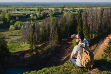 Guy standing on the cliff above the lake with the sky reflecting in it