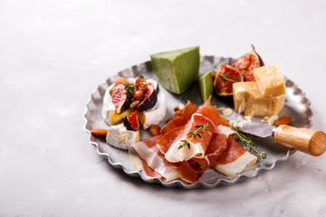 Cheese plate with thyme, a board. A different cheese with fresh figs Honey, walnut almonds and meat. Snack jamon, prosciutto, camembert, parmesan, brie green cheese with basil.selective focus.