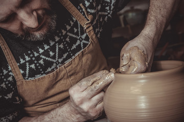 elderly man making pot using pottery wheel in studio