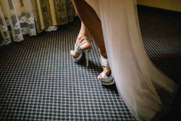 Bride in the dress in the white bridal shoes