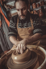 elderly man making pot using pottery wheel in studio