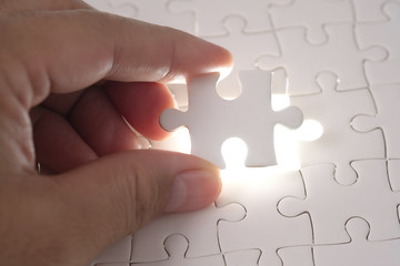 Close up of businessman hands connecting puzzle element and making jigsaw complete