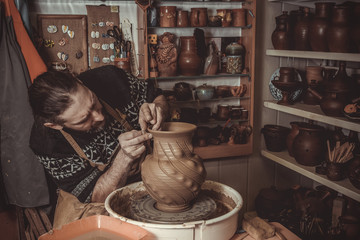elderly man making pot using pottery wheel in studio