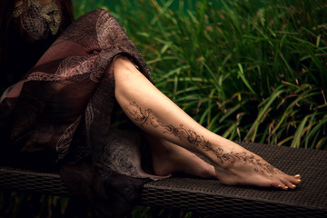 Henna tattoo design on legs. Beautiful indian mehendi ornaments painted on a body part.