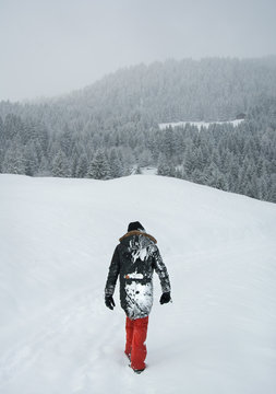 Mann Stapft durch den Schnee in Richtung eines Waldes