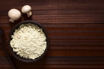 Instant mushroom soup powder in rustic bowl, photographed overhead on dark wood with natural light (Selective Focus, Focus on the soup powder)