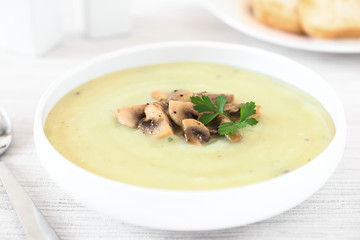 Mushroom cream soup garnished with roasted mushroom slices and parsley, photographed with natural light (Selective Focus, Focus in the middle of the soup)
