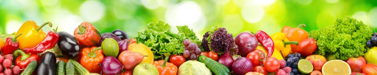 Foto op Plexiglas Groenten Panorama van verse groenten en fruit op onscherpe achtergrond van groene bladeren.