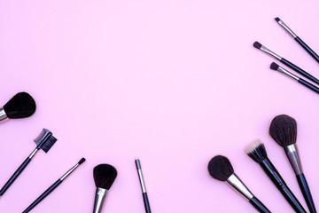 Obraz na płótnie Canvas Set of makeup brushes on pink colored composed background. Top view point, flat lay, space for text.