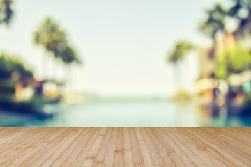 Wood floor with blur summer background tropical resort hotel with swimming pool water and palm tree