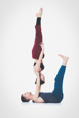 Young athletic couple practicing acroyoga. Balancing in pair