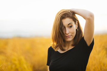 Fototapeta premium Young beautiful girl in the field. She wears a black T-shirt and jeans. Yellow background.