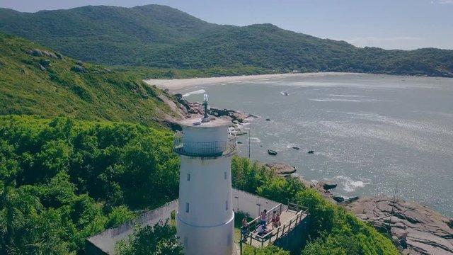 Drone flying by a lighthouse in a paradisiac desert beach in Brazil - praia floripa - praia florianopolis - farol praia