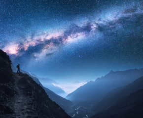 Space with Milky Way, girl and mountains. Silhouette of standing woman on the mountain peak, mountains and starry sky at night in Nepal. Sky with stars. Trekking. Night landscape with bright milky way