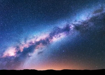 Deurstickers Milky Way. Fantastic night landscape with purple milky way, sky full of stars, yellow light and hills. Shiny stars. Beautiful scene with universe. Space background with starry sky. Astrophotography. © den-belitsky