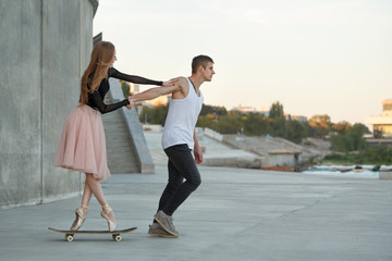 Fototapeta premium Ballerina on a skateboard. The guy helps