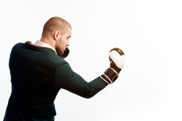 Young bald man, confident business man in white shirt, green suit and boxing gloves doing an uppercut, boxing on white isolated background, sied view.