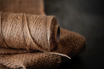 Natural jute twine roll, burlap on black background. Supplies and tools for handmade hobby leisure