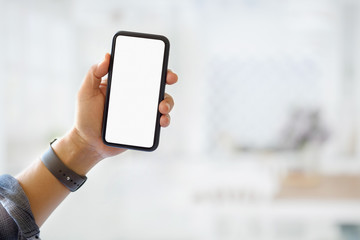 Closes-up shot of man hand holding blank screen smartphone over blurred background.
