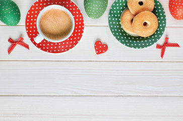 Top view on espresso cup, plate of cookies and  Easter eggs on light wood