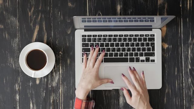 Female user fingers typing on a keyboard of the laptop
