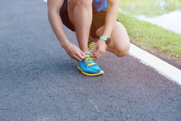 Sport concept, sneakers for running. Man tighting lacing on his sneakers, no face. Legs in professional sport shoes on the track