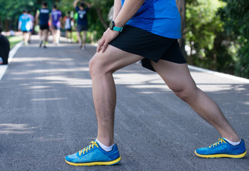 Attractive young man stretching on the track before running, copy space