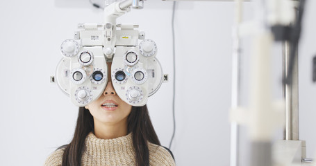 Woman doing eye test in clinic - obrazy, fototapety, plakaty