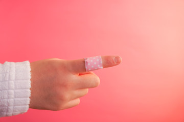 絆創膏を貼った指、絆創膏を貼った手、指差すなど　ピンク背景