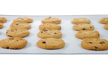 Soft and chewy chocolate chip cookies on a baking tray lined with parchment paper. A popular homemade treat for adults and children alike.