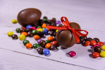 Chocolate easter eggs and multicolored candies on wooden table