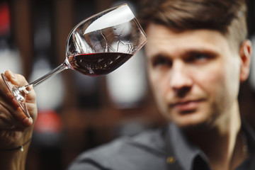 Bokal of red wine on background, male sommelier appreciating drink