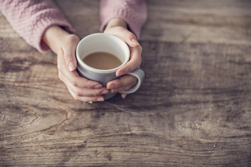 Woman holding coffee mug on wooden background