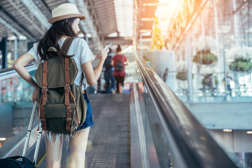 Asian teenage girl is using a smartphone to check flight at the international airport to travel on weekends.