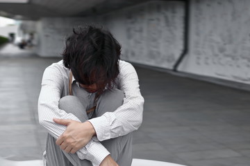 Stressed exhausted young Asian business man suffering from severe depression in office.