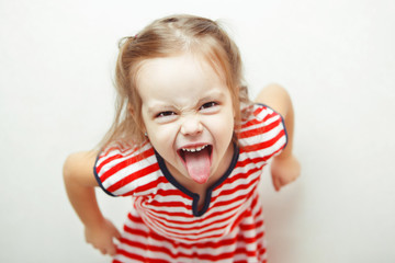 Angry little girl shows her tongue in funny grimace - obrazy, fototapety, plakaty