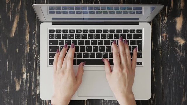 Close-up shot of hands typing something on the laptop keyboard