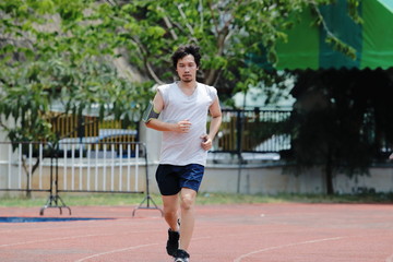 Obraz premium Handsome athlete Asian man running on racetrack in stadium with copy space background. Healthy active lifestyle concept.