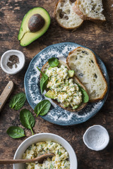 Obraz na płótnie Canvas Avocado, spinach, egg salad on toast sandwich. Healthy food breakfast, snack on wooden background, top view. Flat lay