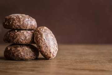 Glazed, chocolate russian gingerbreads or small spice cakes on the dark, wooden vintage table. Enjoying sweets. Snack concept. Empty place for text on the brown background.