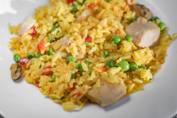 closeup of paella with chicken and seafood on white plate