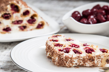 cake with cherries, cream and chocolate on a light wooden background