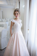 A beautiful woman in a pink wedding dress in a big festive hall