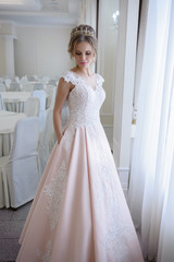 A beautiful woman in a pink wedding dress in a big festive hall