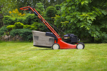 Blurred background of the home garden and lawn mower on mown grass.