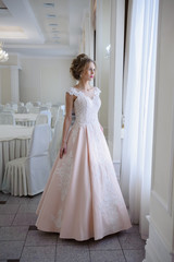 A beautiful woman in a pink wedding dress in a big festive hall