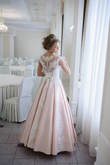 A beautiful woman in a pink wedding dress in a big festive hall