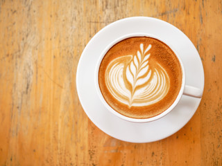 Top view of hot coffee latte with beautiful milk foam latte art texture on wood table grungy background,
